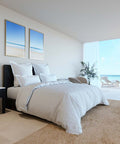 Elegantes weißes Boxspringbett mit weicher Bettwäsche und stilvollen Kissen in modernem Schlafzimmer mit Blick auf das Meer