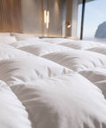 Nahaufnahme einer flauschigen Premium-Daunendecke mit weicher Bettwäsche für hohen Schlafkomfort und luxuriöses Schlafgefühl.