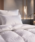 Weiße HANSE Premium Natural Hybrid Kopfkissen am Kopfteil eines Hotelbetts, davor eine bauschige Daunendecke
