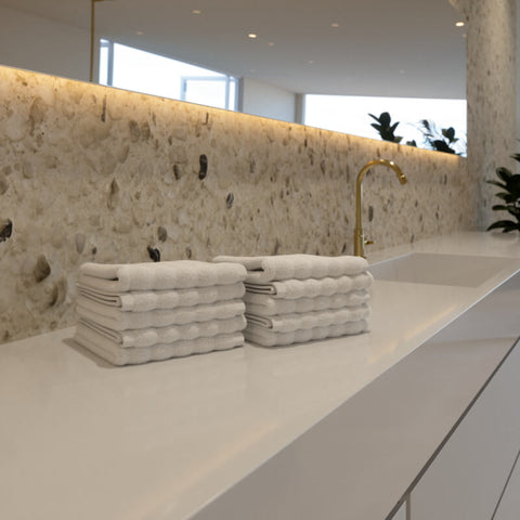 Premium Luxushotel-Waschlappen 10er Set mit sauber gefalteten weißen Waschlappen auf einer modernen Badezimmerablage in exklusivem Hotelambiente.